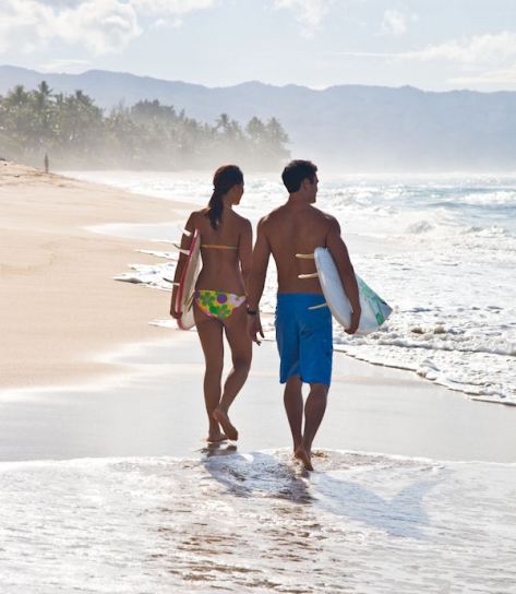 Hawaii couple surfboards walking beach